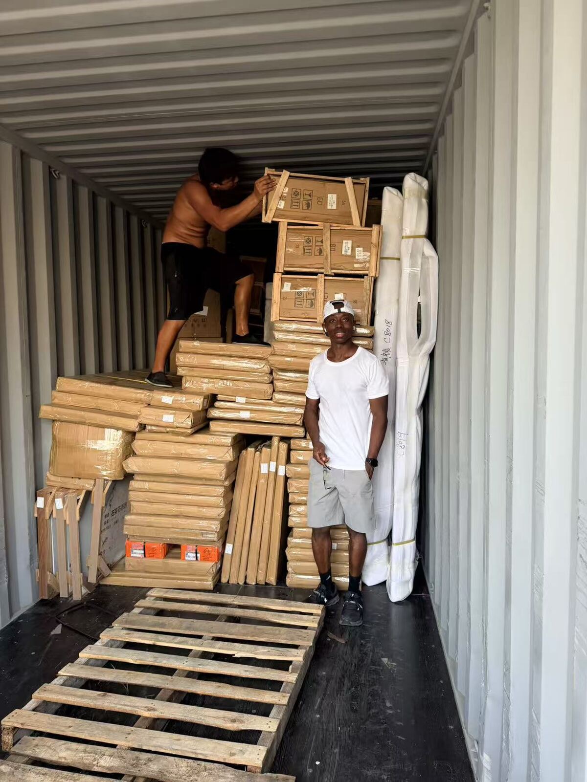Checking items against the packing list while a container is loaded with crated goods