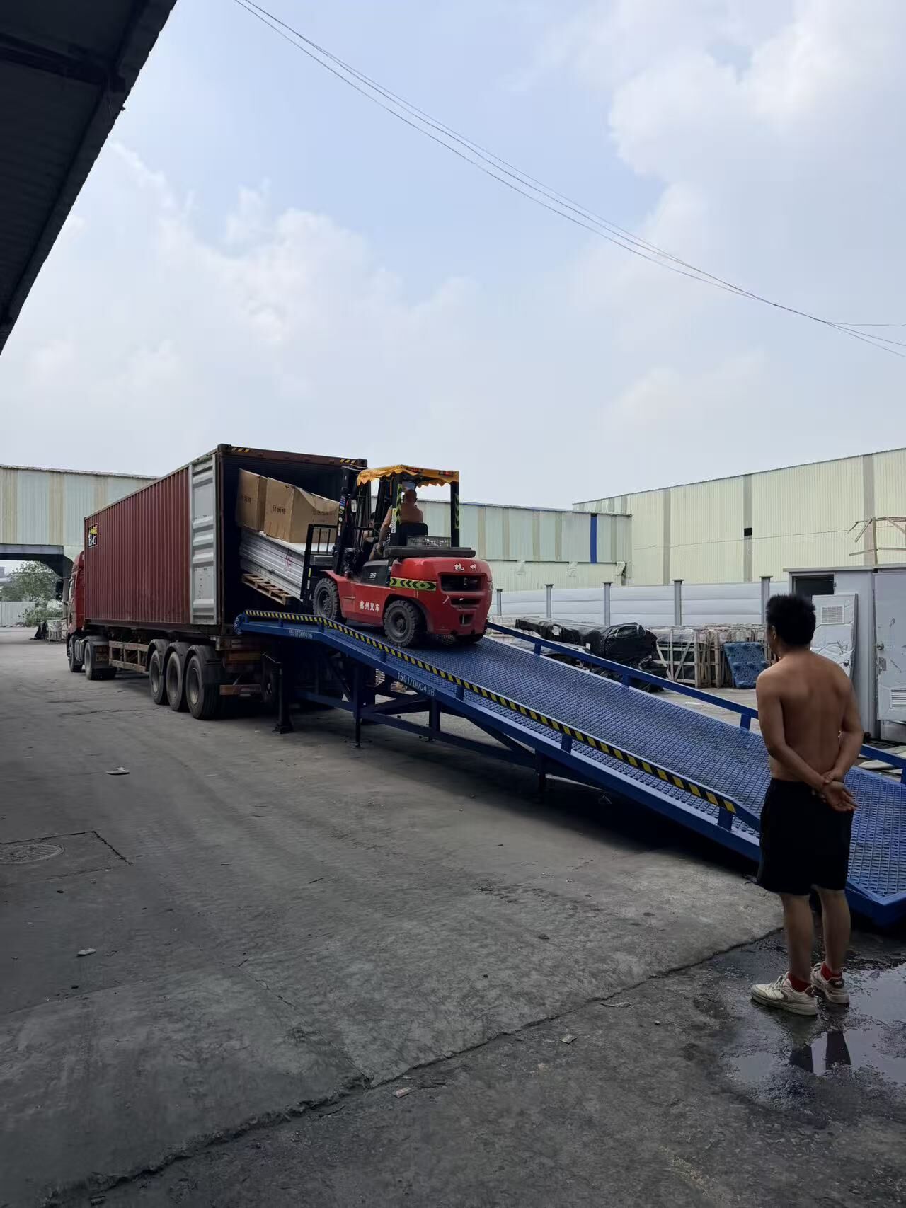 A shipping container being loaded by forklift up a warehouse loading ramp in Guangzhou